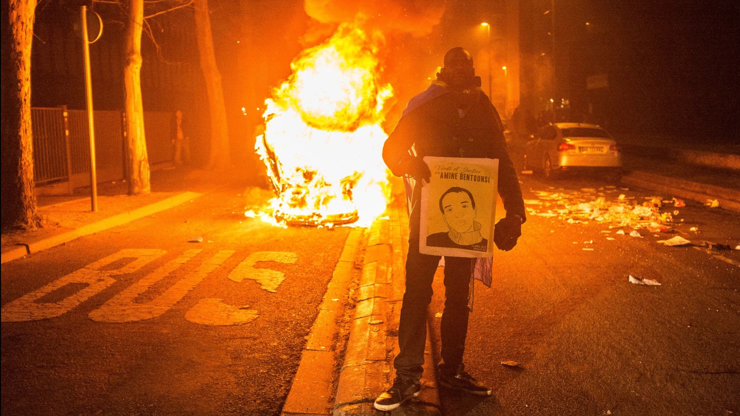 A man stands in front of a burning vehicle on Saturday amid protests in the Bobigny suburb of Paris. 