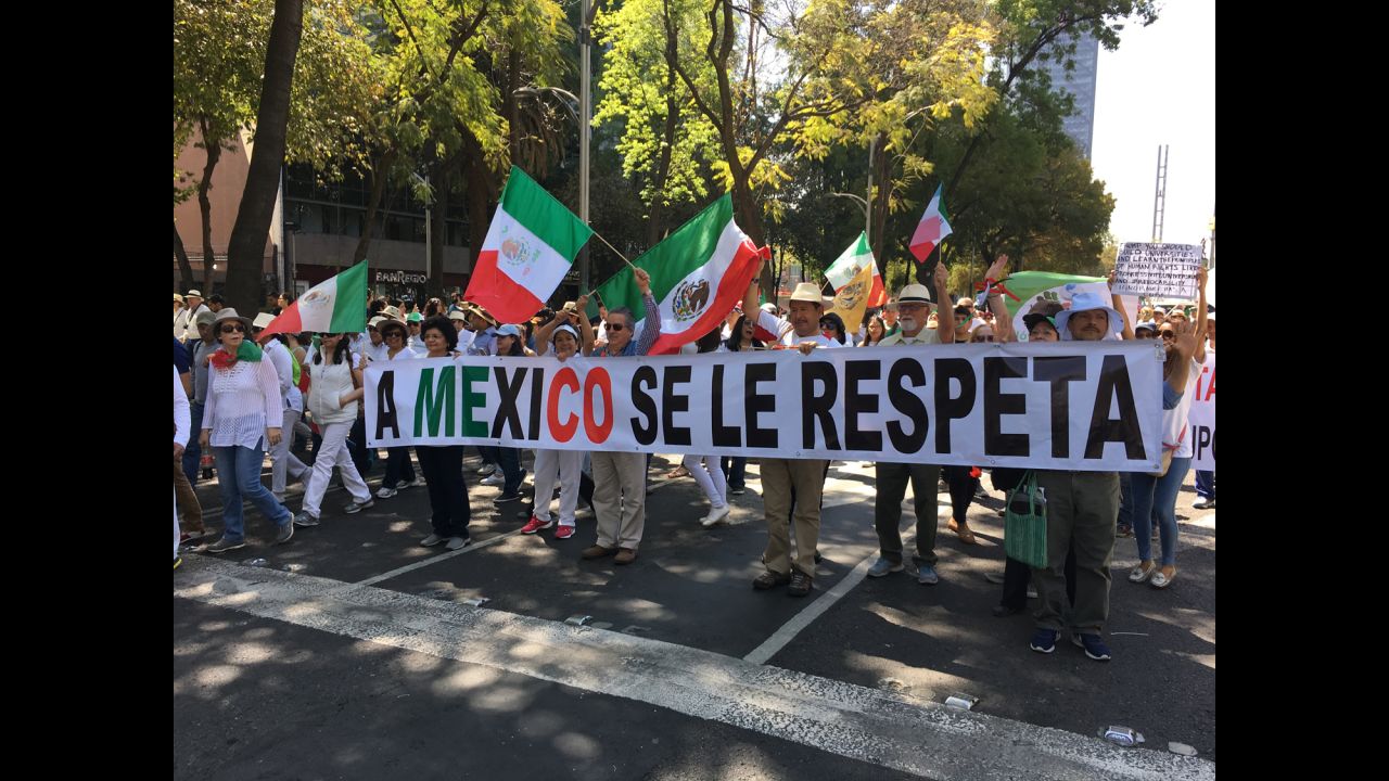 Protesters in Mexico City march behind a banner that says "You respect Mexico."