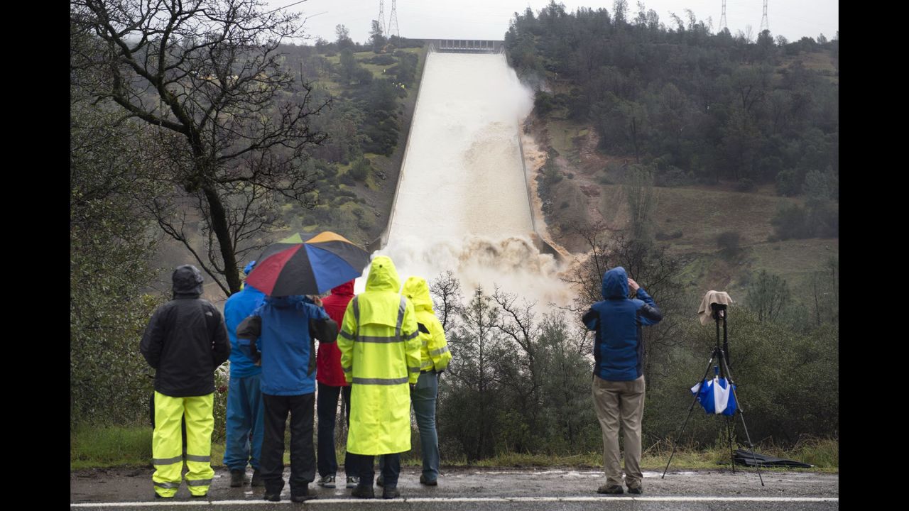 Workers from the Department of Water Resources and members of the media watch as water flows over the main spillway of the Oroville Dam on Wednesday, February 8.