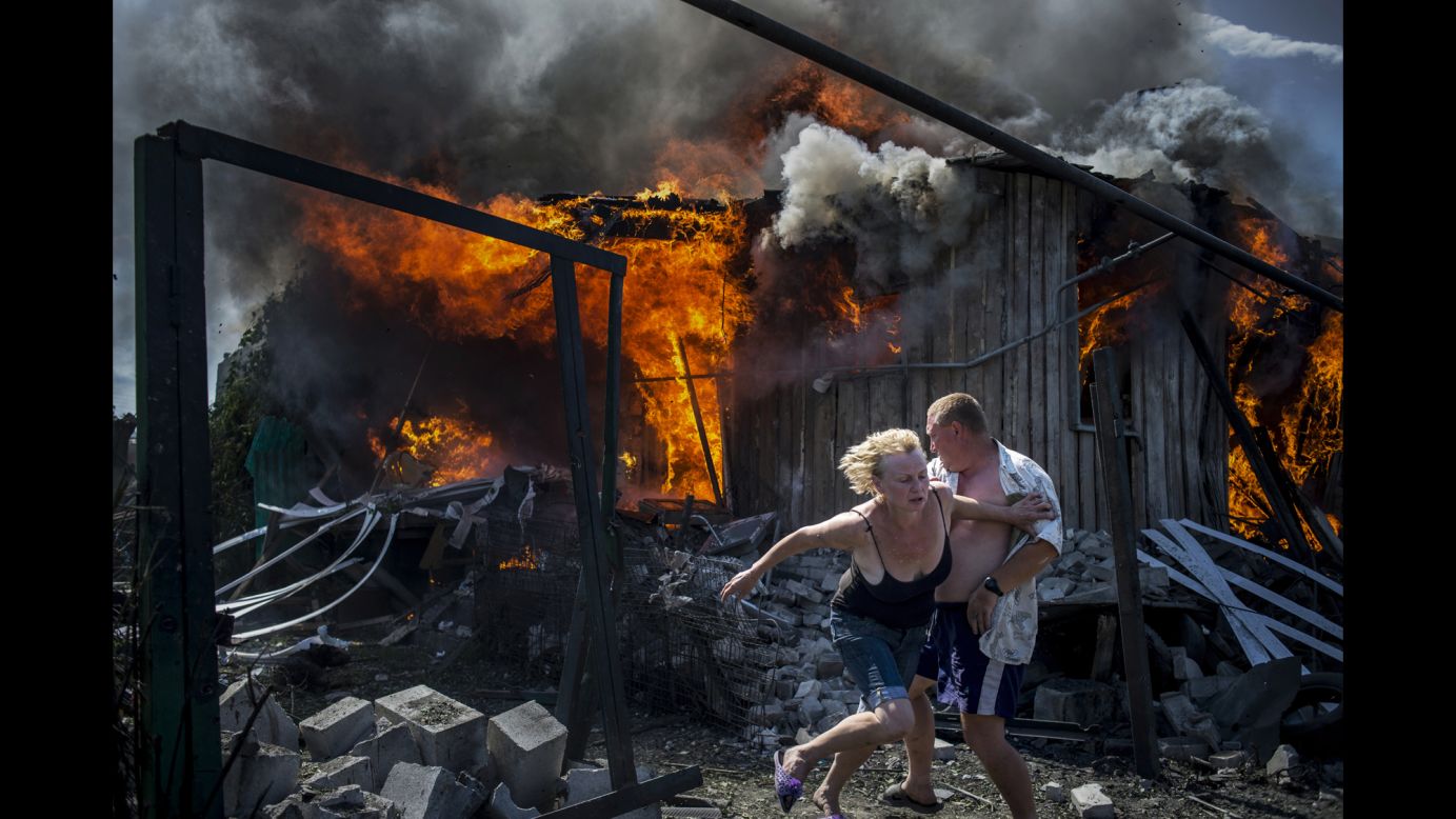 People escape from a fire at a house that was destroyed by an air attack in the Ukrainian village of Luhanskaya. Melnikov's photos show how civilians have been affected by the conflict between Ukraine and pro-Russian rebels.