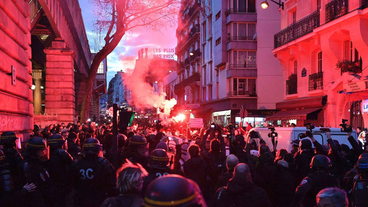 A smoke flare lights up the crowd at an anti-police protest in Paris.