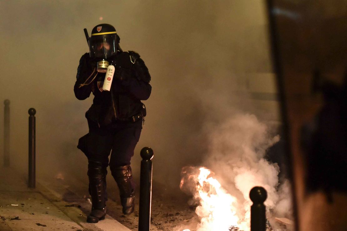 A riot policeman holds a tear gas canister at the Paris protest.