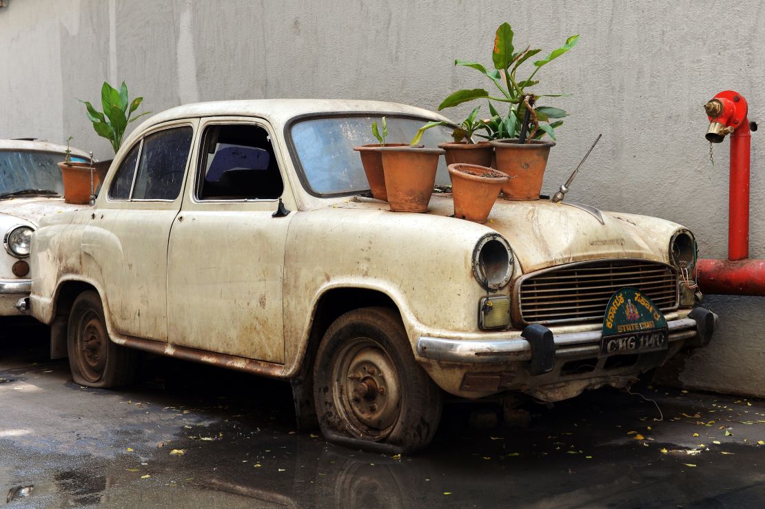 An old defunct Ambassador "State Car" hosts plant bearing pots at the basement of a government building in Bangalore on May 30, 2014 -- the year production was stopped.