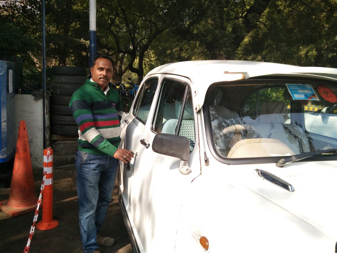 Rajkumar Kapoor, a driver in Delhi, stands with the Ambassador car that he drives.