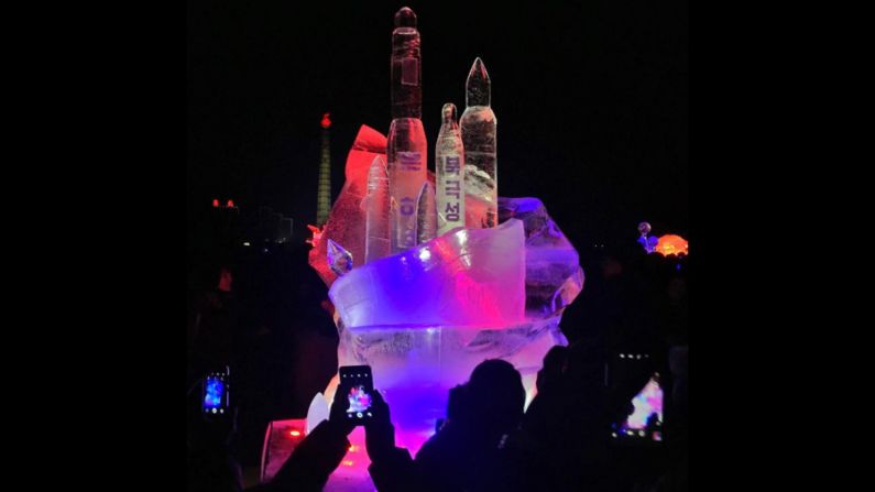 People use smartphones on on February 16, to take photos of an ice sculpture in Pyongyang.