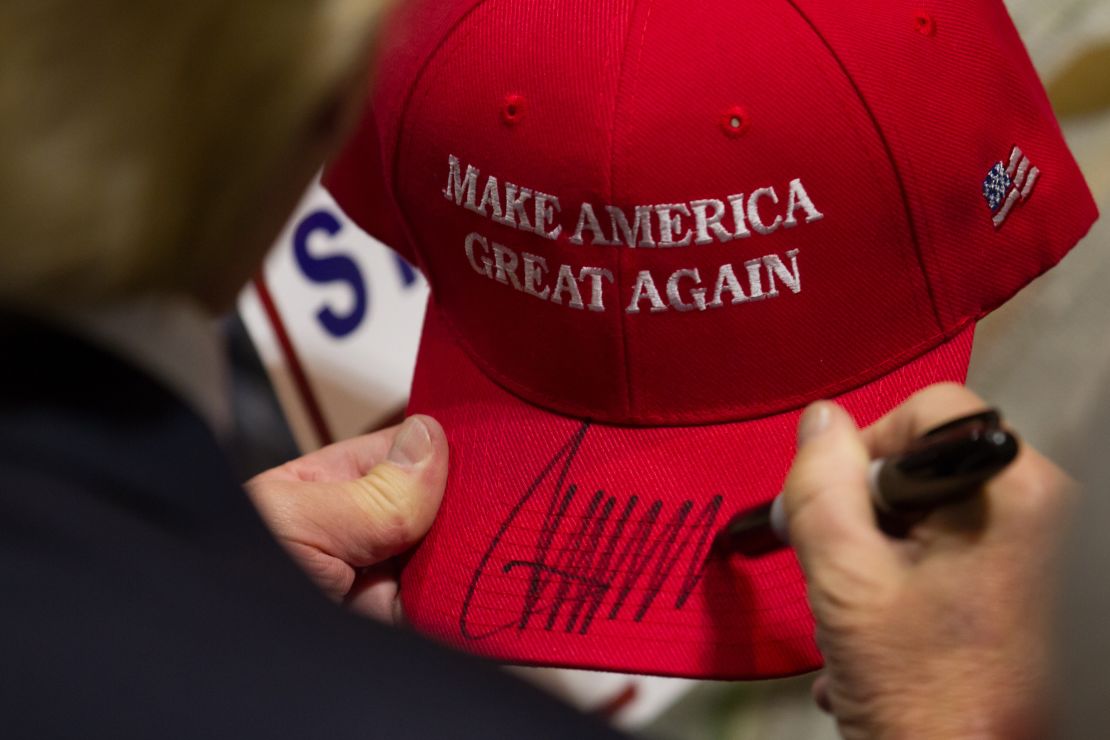 Donald Trump signs a hat after speaking at a campaign rally.