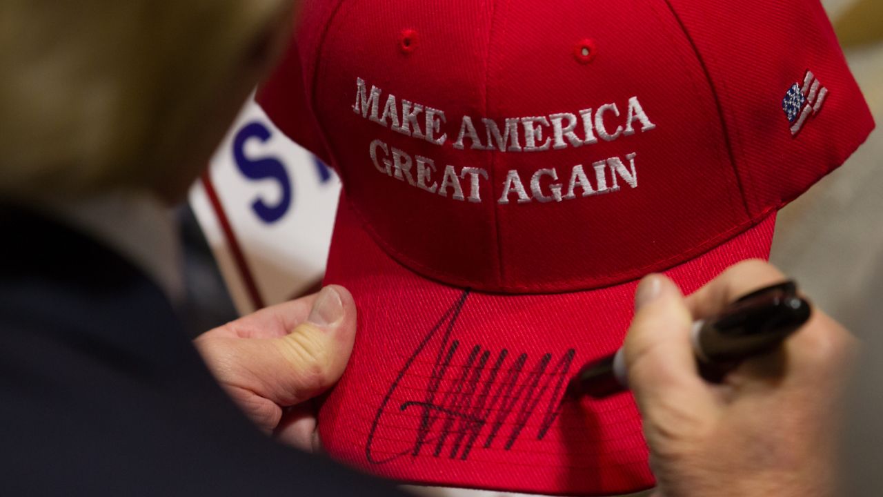 Donald Trump signs a hat after speaking at a campaign rally.