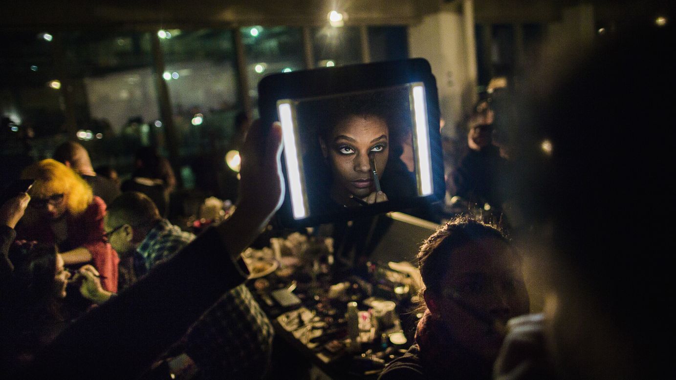 A makeup artist works on a model as an assistant lights the model's face during a fashion show in New York on Tuesday, February 14.