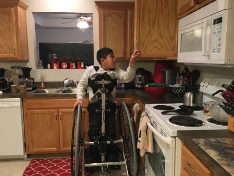Jason opens a kitchen cupboard, December 9, 2016.  His adoptive parents, Brian and Jeri Wilson, are building a new home that's wheelchair accessible.