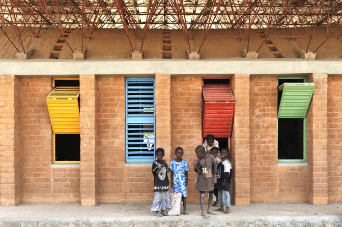 His first project, a primary school in his hometown of Gando, was built while still a student in Berlin. To fund it, Kéré created an association, Schulbausteine für Gando.<br /><br />Frugally created on a budget of less than $30,000 it earned him the prestigious Aga Khan Award for Architecture in 2004 and further extensions to the school bagged the 2009 Global Award for Sustainable Architecture.