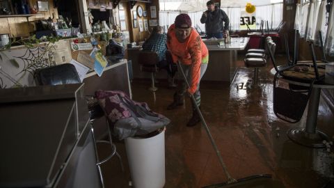 Tina Dry mops up water and mud that seeped into her family's diner, Kim's Country Cafe, after area storms brought flood-level water to the Colusa County town of Maxwell on February 18. 