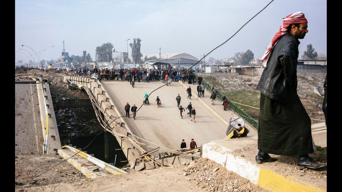Mosul residents cross a damaged bridge in the al-Sukkar neighborhood on Saturday, January 21.