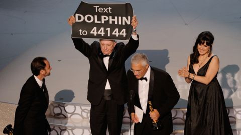 When Louie Psihoyos and Fisher Stevens won the best documentary feature award for "The Cove" at the 82nd Academy Awards on March 7, 2010, they were accompanied on stage by producer Paula DuPré Pesmen and film subject Ric O'Barry. O'Barry walked on stage carrying a sign that prompted the audience to text for more information on how to help curtail the dolphin slaughter depicted in the film.