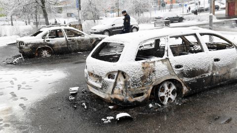 A policeman investigates a burned-out car in Rinkeby, Stockholm, after riots broke out.