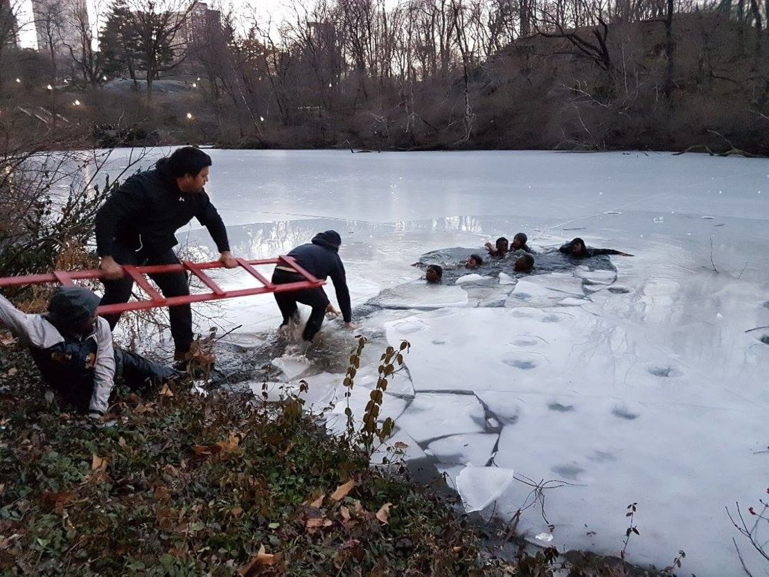 People extend a ladder to help teens out of ice water in Central Park.
