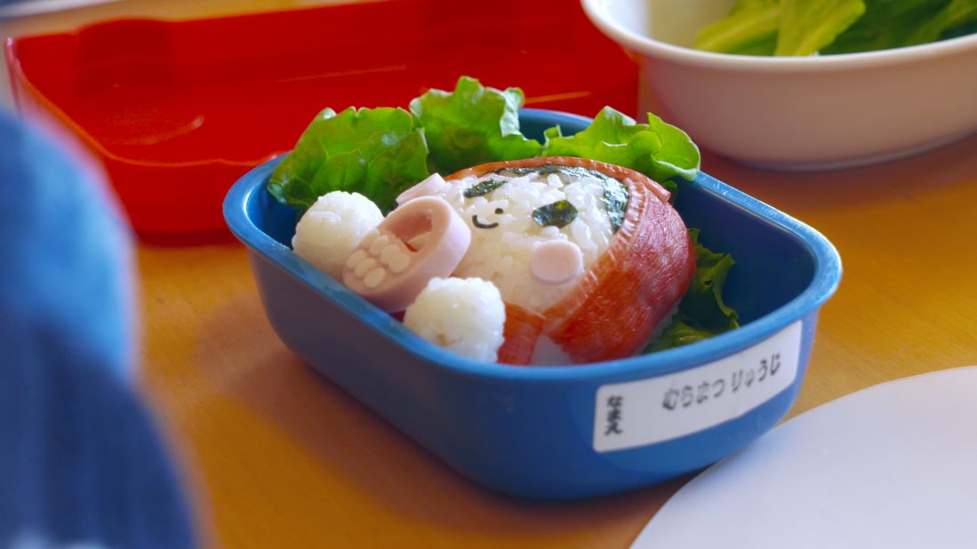 Maruo teaches other moms how to make faces on rice balls using ham, crab, fish cakes, eggs, vegetables, and seaweed.