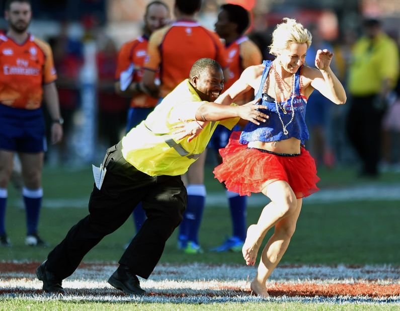 A security guard chases a costumed fan after she ran on the pitch during the 2015 Cup Final match between Fiji and New Zealand.