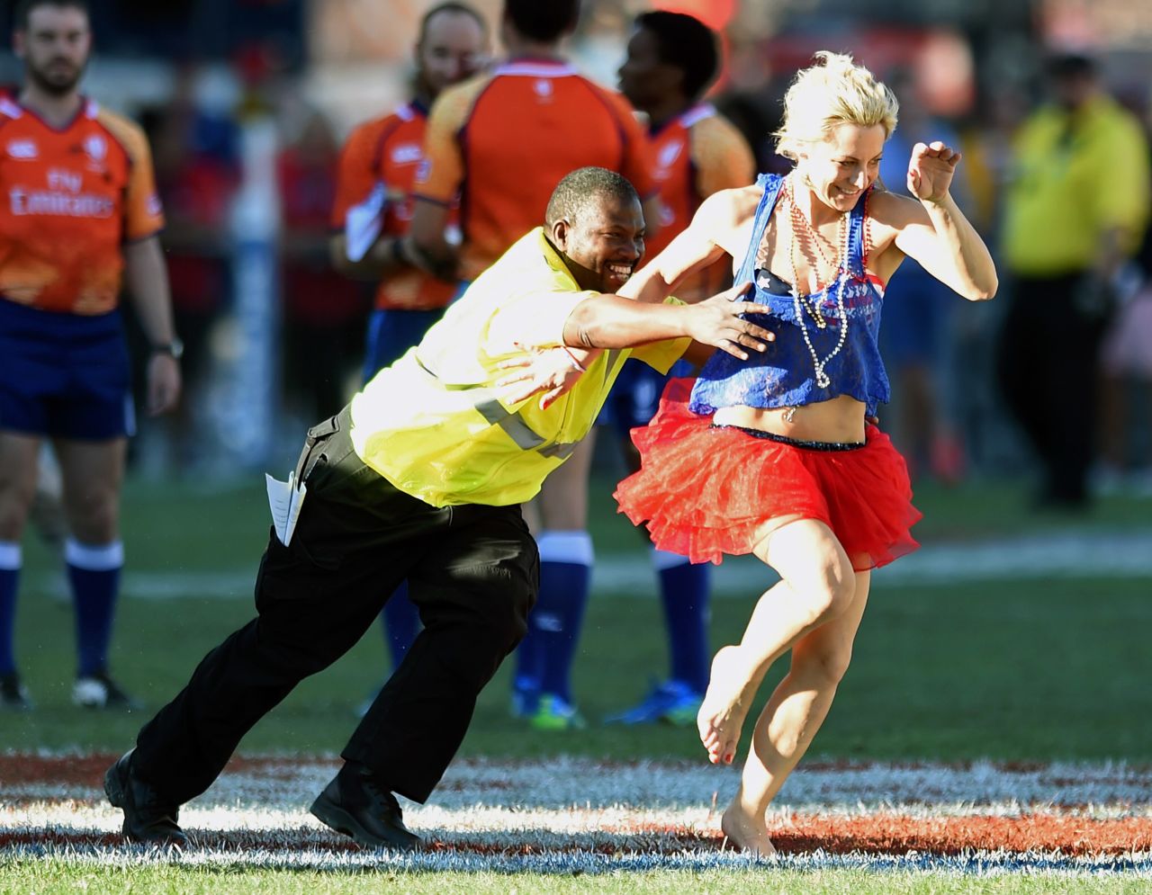 A security guard chases a costumed fan after she ran on the pitch during the 2015 Cup Final match between Fiji and New Zealand.