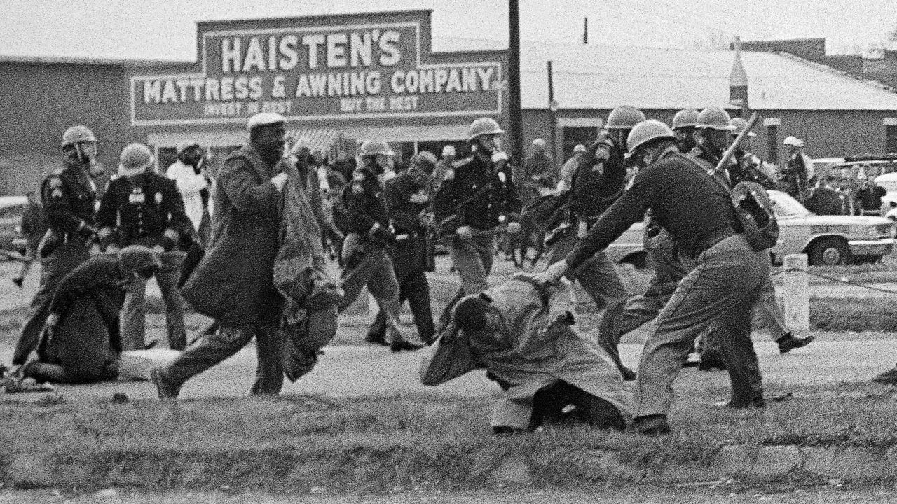 State troopers swing billy clubs to break up the march on "Bloody Sunday." In the foreground, activist John Lewis is being beaten. He suffered a fractured skull. Lewis is now a US congressman.