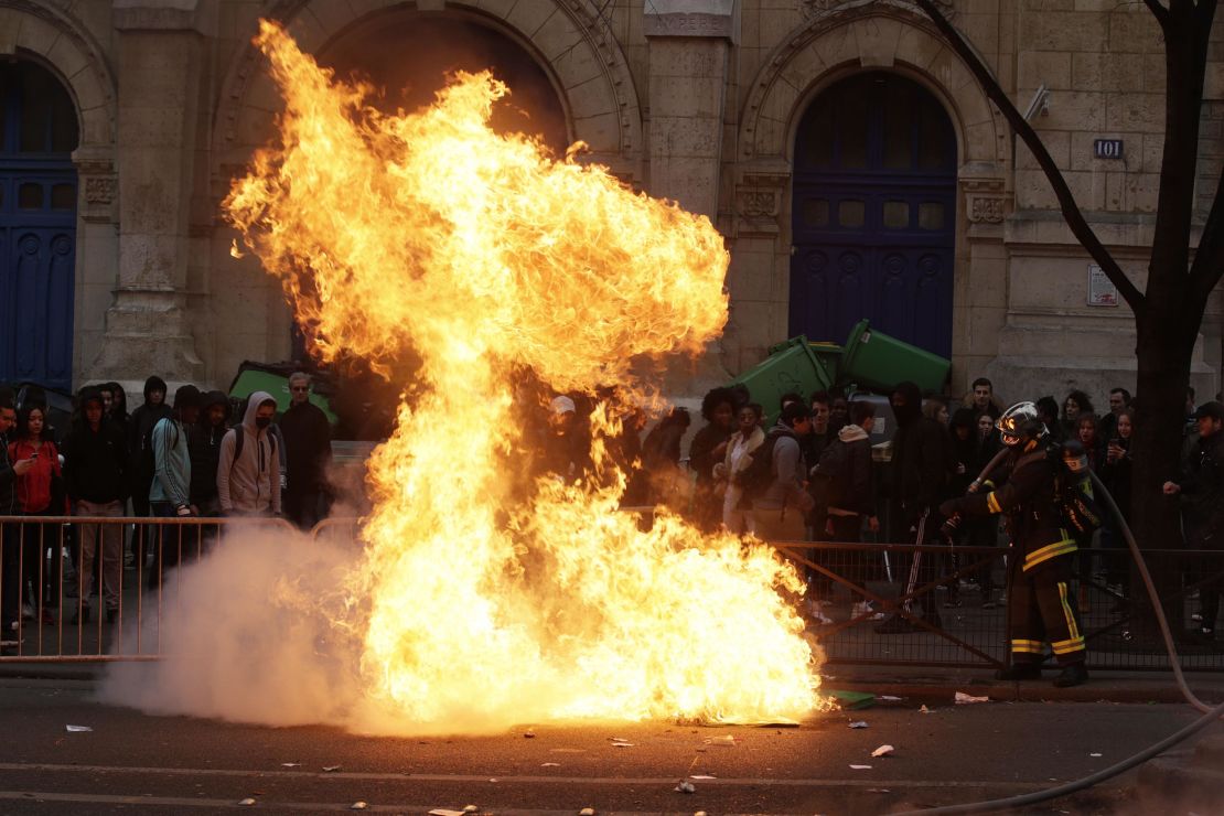 Firemen try to extinguish burning dustbins at Paris protest.