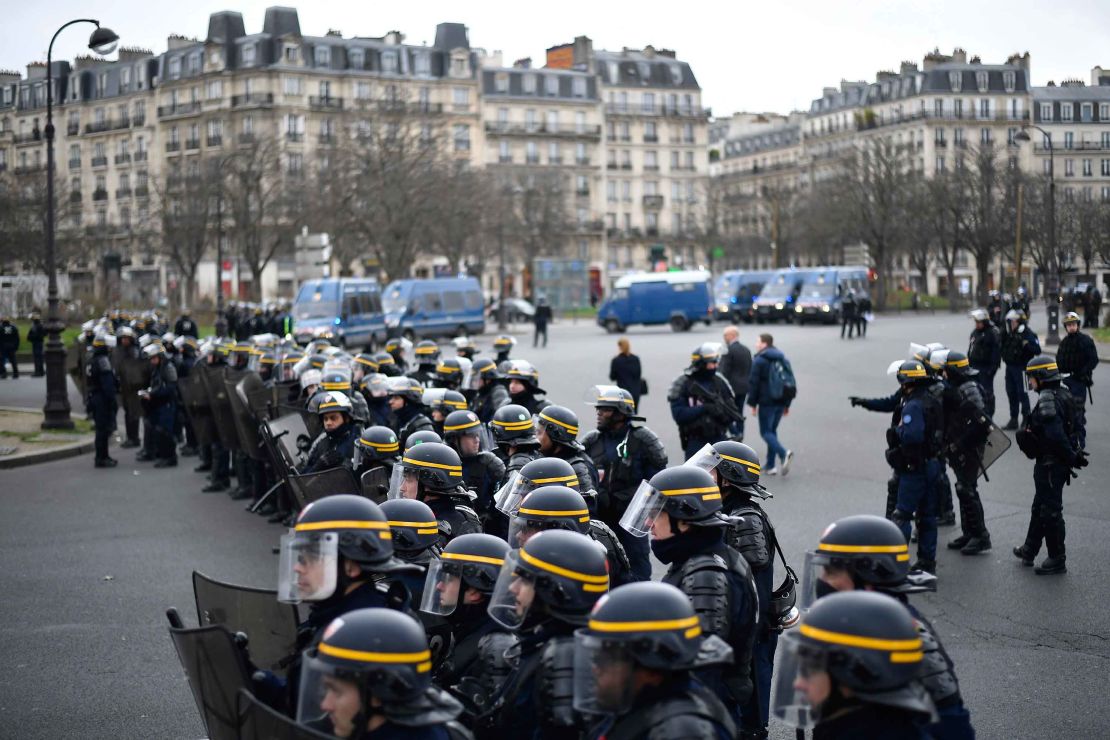Riot police forces stand guard.