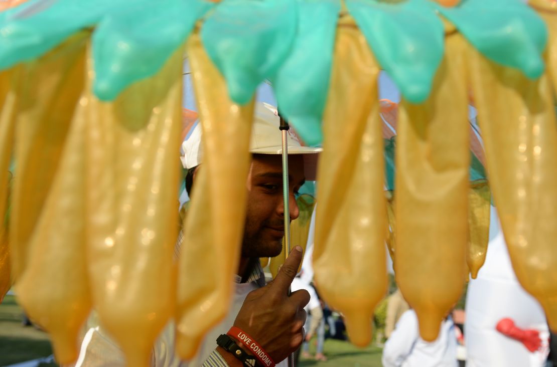 An Indian volunteer holds an umbrella decorated with condoms during an event to mark International Condom Day in New Delhi on February 13, 2017.
