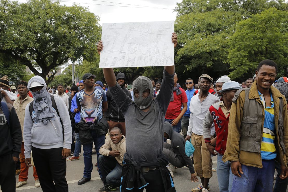 A South African holds a sign calling for foreign residents to leave the city during a march in Pretoria. 