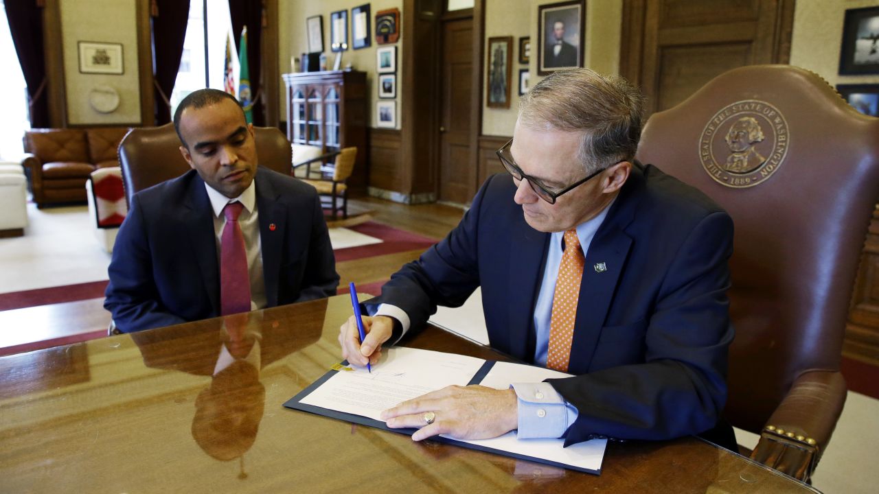 Washington Gov. Jay Inslee -- at right, next to general counsel Nick Brown -- signs an executive order Thursday, February 23, to restrict state workers and agencies from enforcing President Trump's immigration policies. Inslee has been outspoken about the Trump administration, and he said his order reaffirms the state's commitment to tolerance.