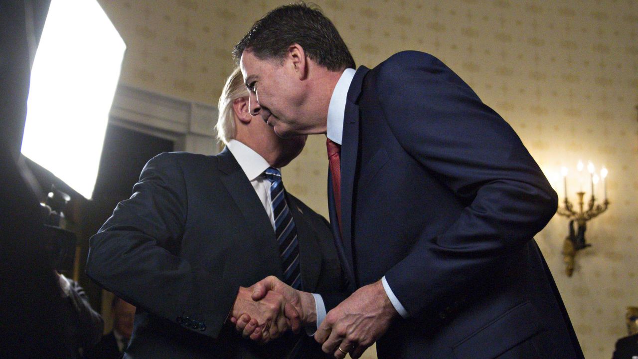 WASHINGTON, DC - JANUARY 22: U.S. President Donald Trump (L) shakes hands with James Comey, director of the Federal Bureau of Investigation (FBI), during an Inaugural Law Enforcement Officers and First Responders Reception in the Blue Room of the White House on January 22, 2017 in Washington, DC. Trump today mocked protesters who gathered for large demonstrations across the U.S. and the world on Saturday to signal discontent with his leadership, but later offered a more conciliatory tone, saying he recognized such marches as a "hallmark of our democracy." (Photo by Andrew Harrer-Pool/Getty Images)