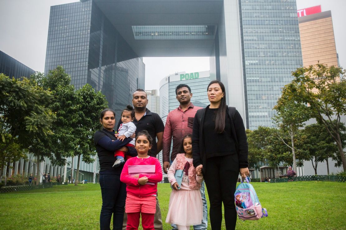Sri Lankan refugee Supun Thilina Kellapatha (3rd L), 32, his partner Nadeeka (L), 33, with their baby boy Dinath, daughter Sethumdi, 5, Sri Lankan refugee Ajith Puspa (3rd R), 45, and Filipino refugee Vanessa Rodel (R), 40, with her daughter Keana, 5, pose for a photo in front of the government buildings of Hong Kong on February 23, 2017.
