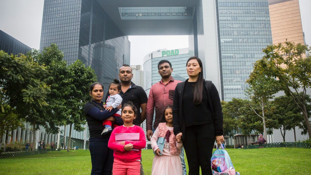 Sri Lankan refugee Supun Thilina Kellapatha (3rd L), 32, his partner Nadeeka (L), 33, with their baby boy Dinath, daughter Sethumdi, 5, Sri Lankan refugee Ajith Puspa (3rd R), 45, and Filipino refugee Vanessa Rodel (R), 40, with her daughter Keana, 5, pose for a photo in front of the government buildings of Hong Kong on February 23, 2017.