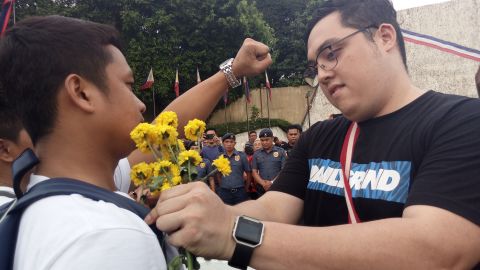 An anti-Duterte protester apologizes with a flower to a Duterte supporter.