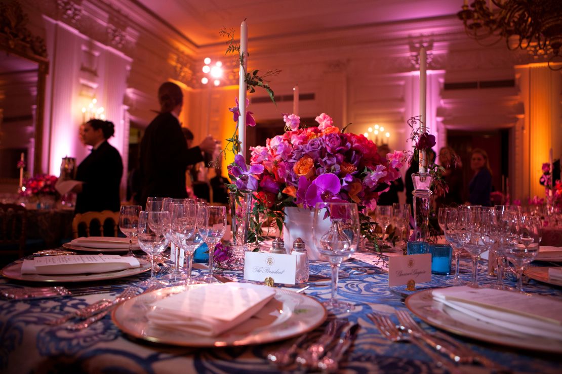 White House State Dining Room 2011. A vivid bouquet of orange and fuchsia flowers with accents of hot pink Phalaenopsis orchids makes a strong statement for the annual National Governors Association Dinner at the White House state dining room. The historic "Charleston" candlesticks are wrapped with blooming jasmine vine. The Lady Bird and President Johnson china service, featuring wildflowers from across America, reflects the gathering of Governors from all 50 states. 