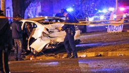 Police officers chat with a man in a car that was struck by a pickup.