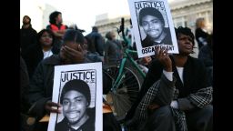 OAKLAND, CA - JANUARY 14:  Protestors carry signs with a picture of slain 22-year-old Oscar Grant III during a demonstration at Oakland City Hall January 14, 2009 in Oakland, California. Twelve days after the fatal shooting of Oscar Grant III, former Bay Area Rapid Transit (BART) police officer Johannes Mehserle was arrested and charged with murder for shooting Grant in the back as he lay face down on the ground following an altercation on a BART train. (Photo by Justin Sullivan/Getty Images)