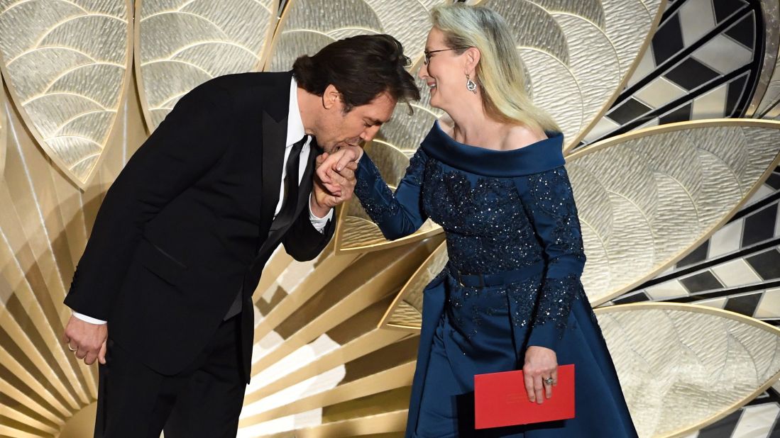 Javier Bardem kisses Meryl Streep's hand as they present an award.
