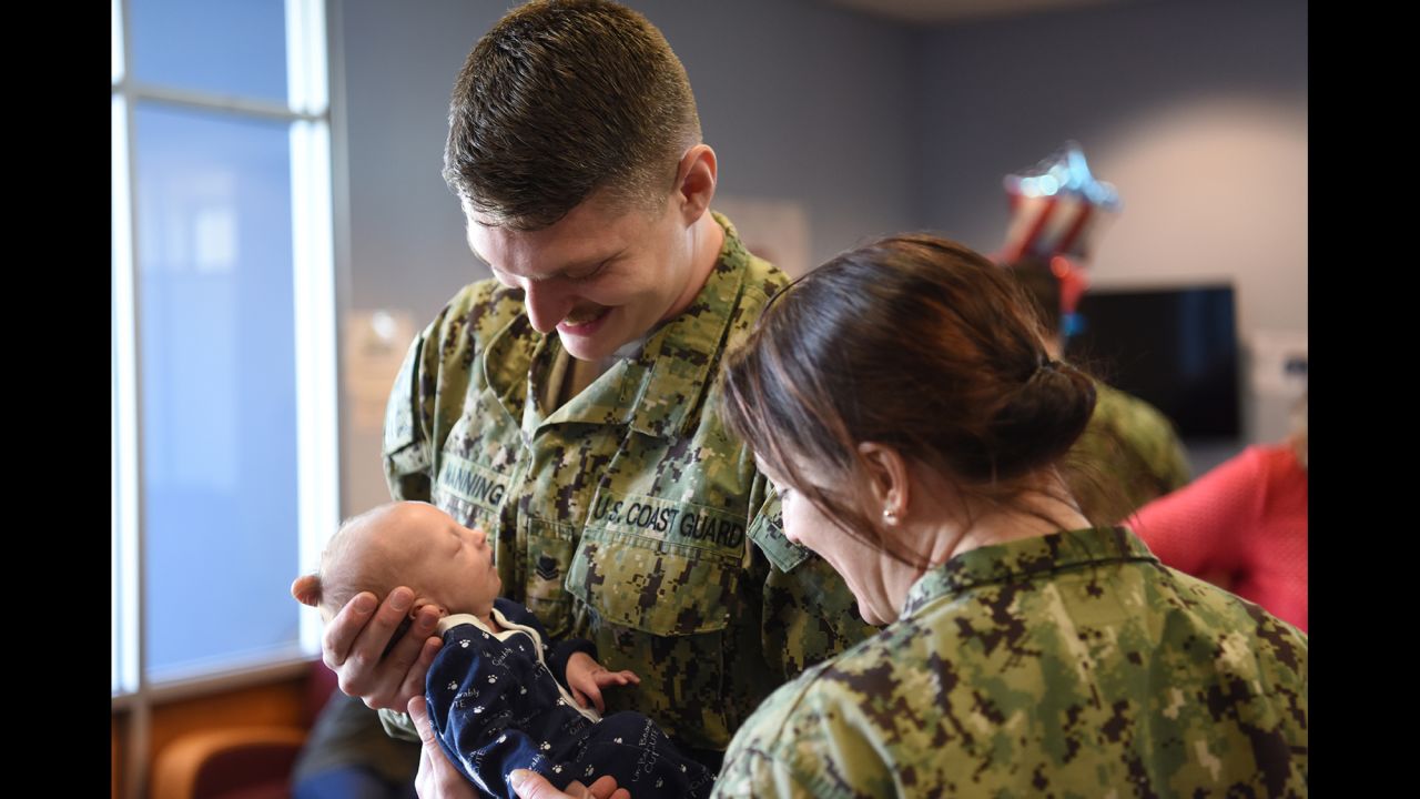 Coast Guard Petty Officer 2nd Class Benjamin Manning holds his baby in Norfolk, Virginia, before going on a nine-month deployment on Monday, February 13.
