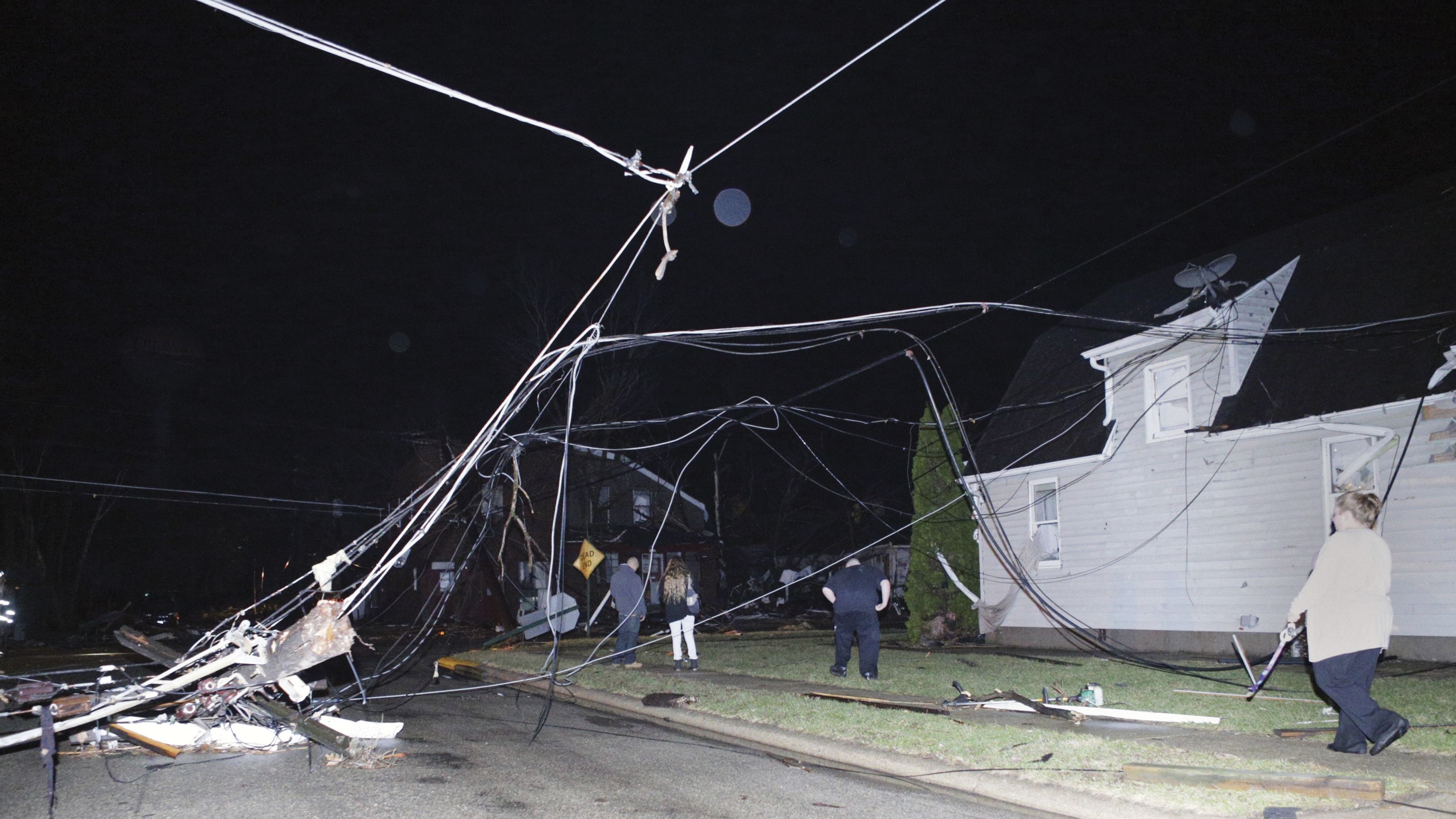 People walk past downed wires after a storm moved through Naplate, Illinois, on Tuesday. 