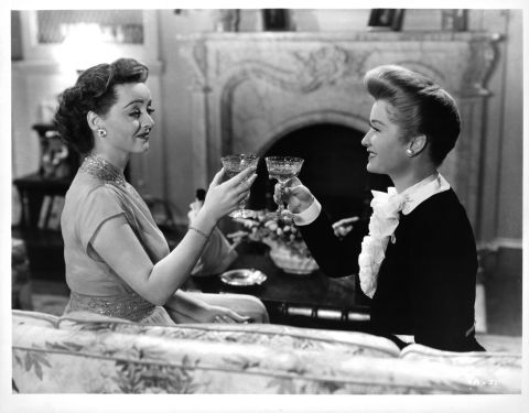 Davis toasts Miriam Hopkins in the final scene of "Old Acquaintance" (1943), about two longtime writer friends who are rivals in love and literature. The movie was a follow-up to the stars' 1939 teaming in "The Old Maid." Davis had the sympathetic part in both movies, which may have prompted Hopkins to pull out all her scene-stealing tricks. "Miriam is a perfectly charming woman socially. Working with her is another story," Davis said in "The Lonely Life."