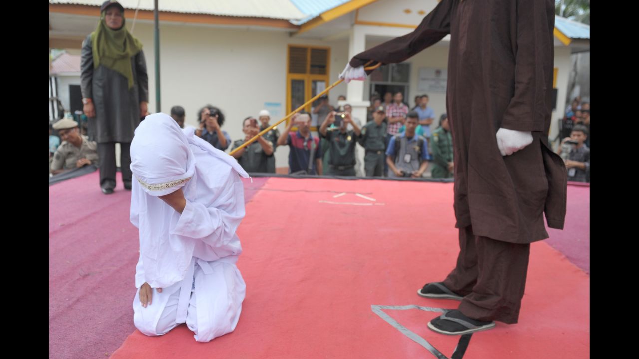 A woman is caned by a religious officer in Banda Aceh, Indonesia, on Monday, February 27. The province of Aceh is strictly Muslim and is the only province in the country implementing Sharia law. Public canings happen there regularly and often attract huge crowds. The woman here was being punished for spending time in close proximity with a man who is not her husband.