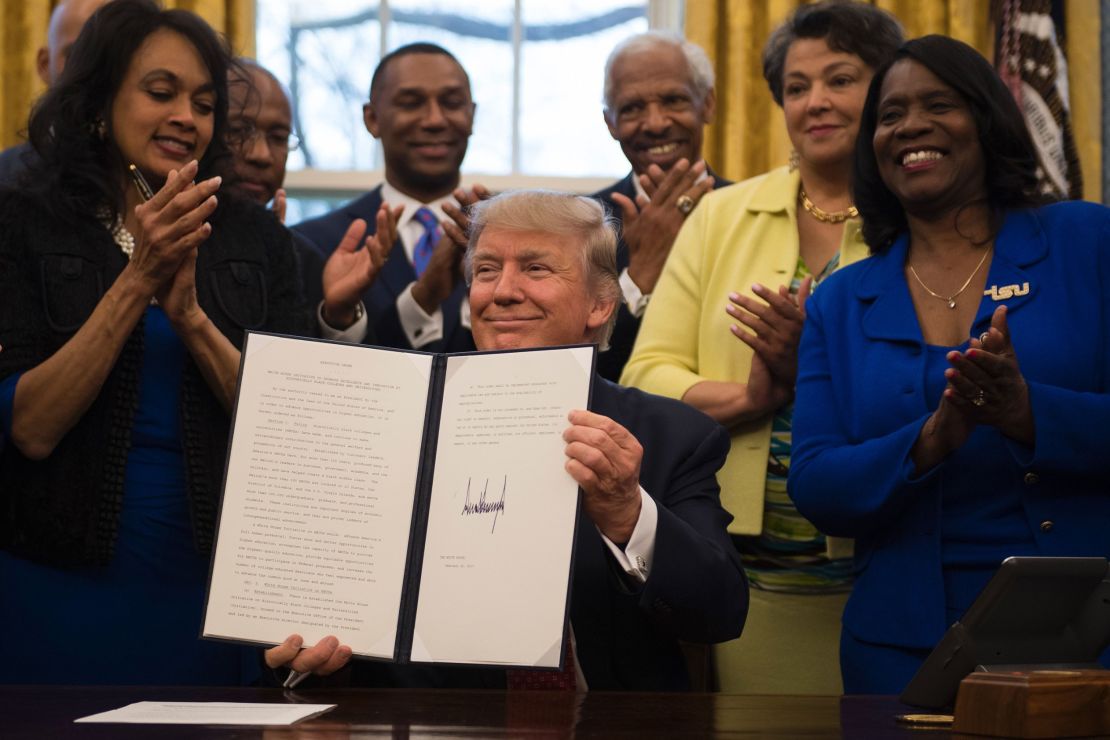 President Donald Trump holds up the executive order.