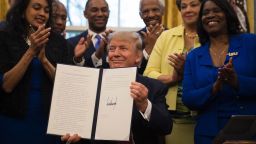 President Donald Trump holds up an executive order to bolster historically black colleges and universities (HBCUs) in the Oval Office of the White House on February 28, 2017.
