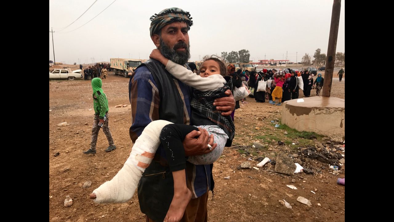 An Iraqi man carries his daughter, wounded by a mortar round that slammed into their home in the Ma'moun neighborhood of Mosul. Many of those fleeing were said to have been held as human shields by ISIS fighters while their neighborhoods became battlefields.