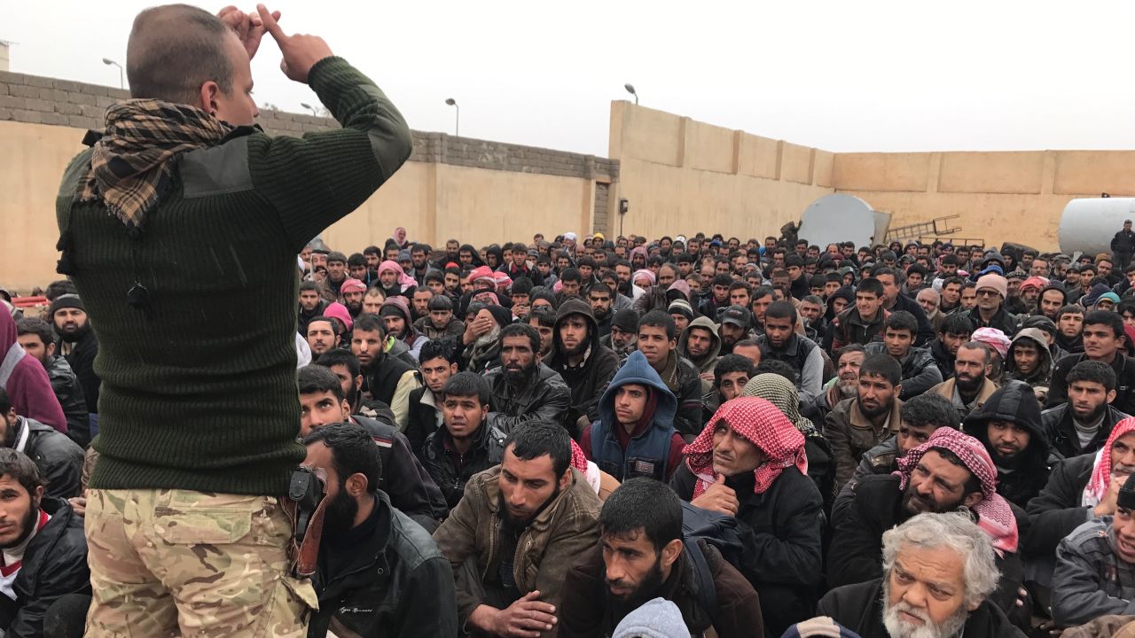 An Iraqi security officer talks to hundreds of detained men and boys who fled western Mosul. The group gathered at a processing facility south of Mosul before being transferred to nearby refugee camps.