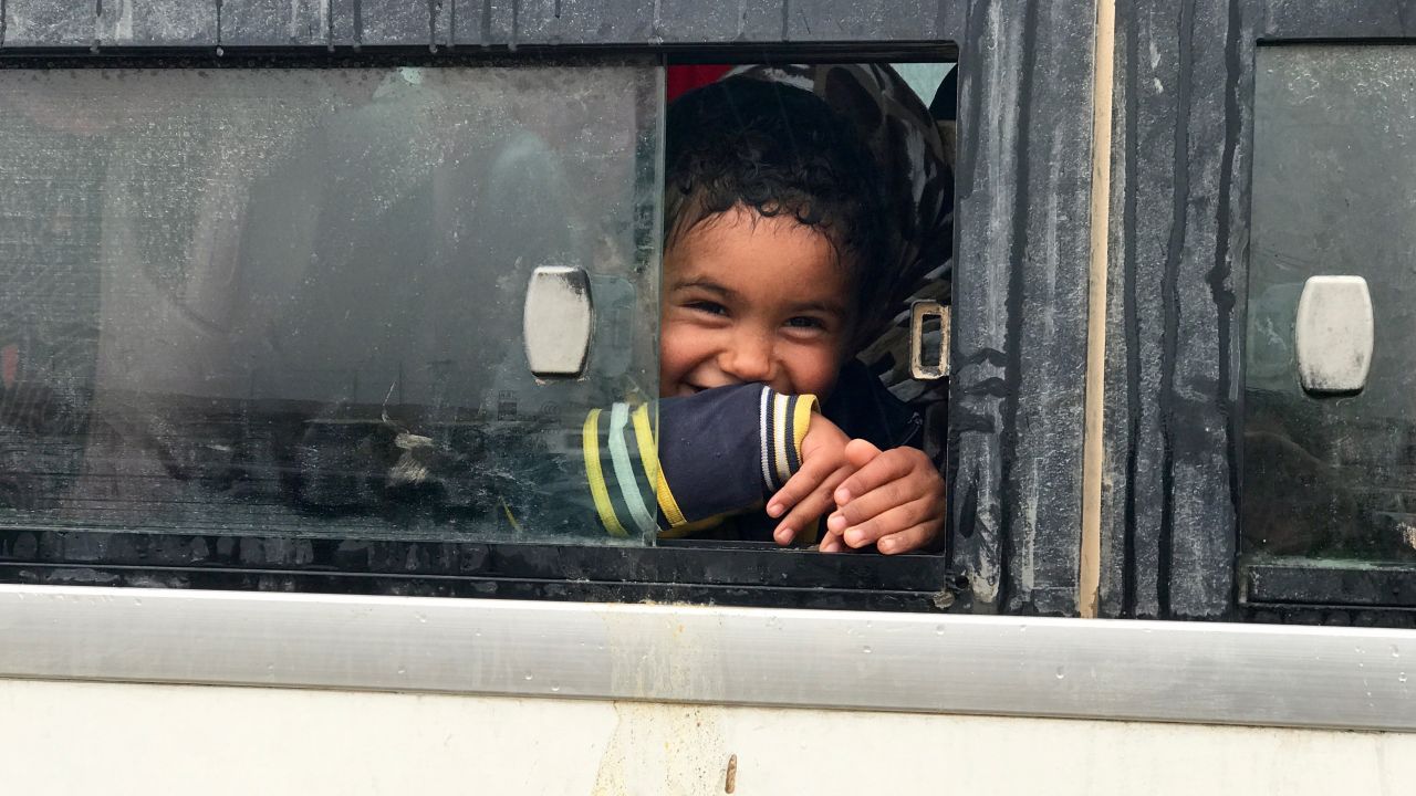 A young Iraqi boy smiles as he sits on a bus before being transported with his mother and other civilians fleeing western Mosul to a nearby refugee camp.