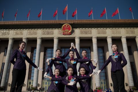 Hostesses pose for a picture in front of the Great Hall of the People.