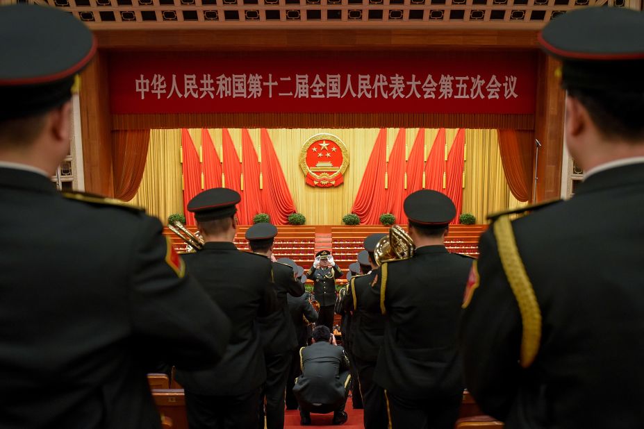 A Military orchestra conductor leads the band as a military photographer takes his portrait after the opening session.