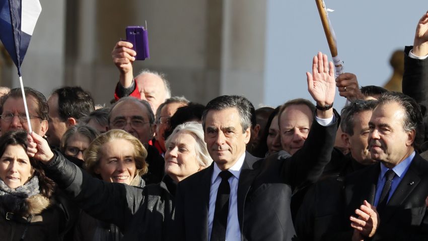 French presidential election candidate for the right-wing Les Republicains (LR) party Francois Fillon (C), flanked by his wife Penelope Fillon (3rd L) and French lawmaker Luc Chatel (2nd R), gestures on stage as supporters holding French flags greet him during a rally at the place du Trocadero, in Paris, on March 5, 2017.
Embattled French conservative Francois Fillon told supporters at a Paris rally on March 5, 2017 to "never give up the fight" as he strives to stay in the presidential election race amid an expenses scandal. Fillon, who is to be charged over claims he gave his wife and children highly-paid fake parliamentary jobs, told the rain-drenched crowd he had been "attacked by everyone" in the campaign.
 / AFP PHOTO / Thomas SAMSON        (Photo credit should read THOMAS SAMSON/AFP/Getty Images)