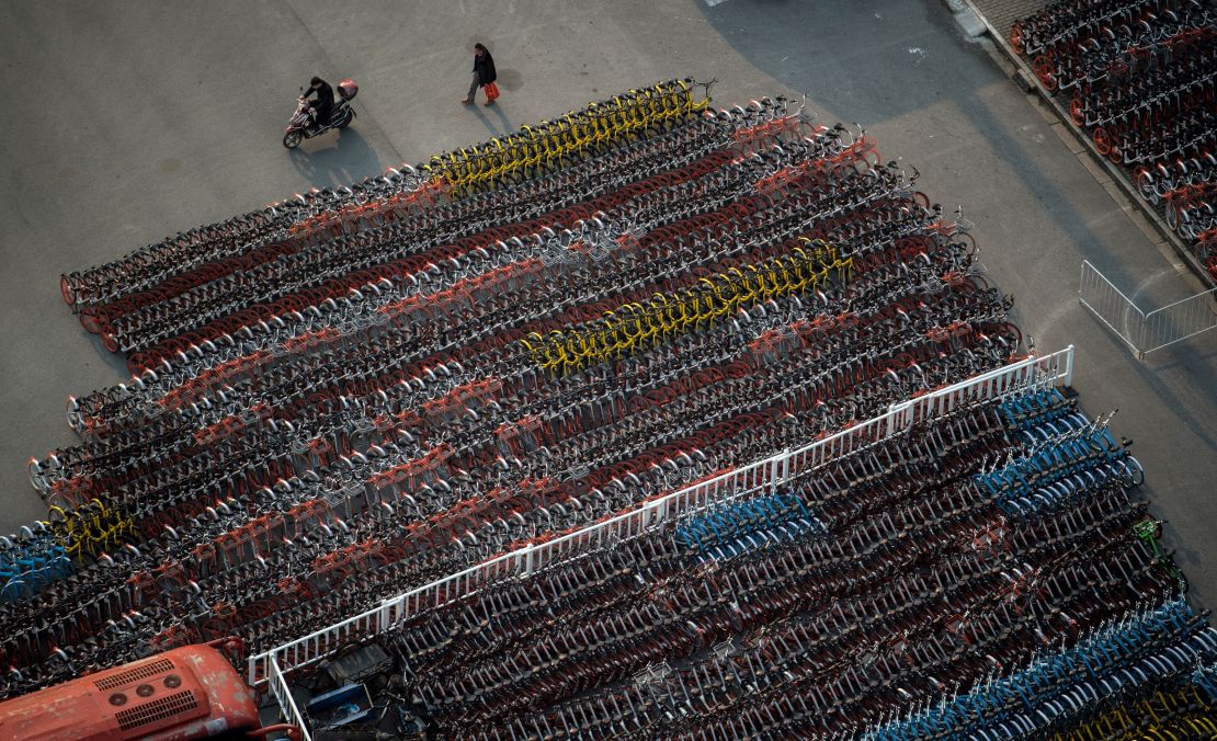 A man walks past impounded bicycles from the bike-sharing schemes Mobike and Ofo in   Shanghai on March 1, 2017.  
