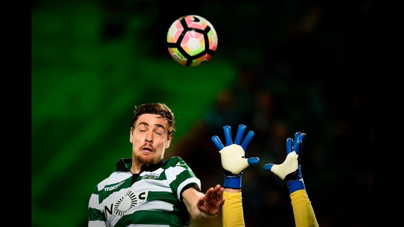 A goalkeeper reaches for the ball as Sporting Lisbon defender Sebastian Coates heads it during a match in Portugal on Sunday, March 5.